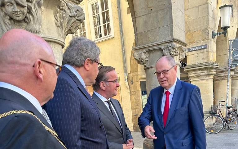 Mehrere Politiker stehen vorm Rathaus in Münster.