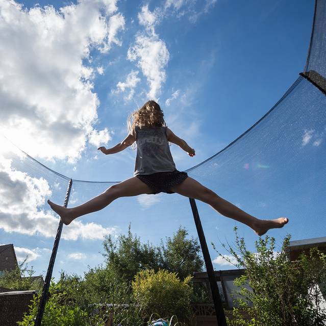 Ein Mädchen springt in einem Garten auf einem Trampolin