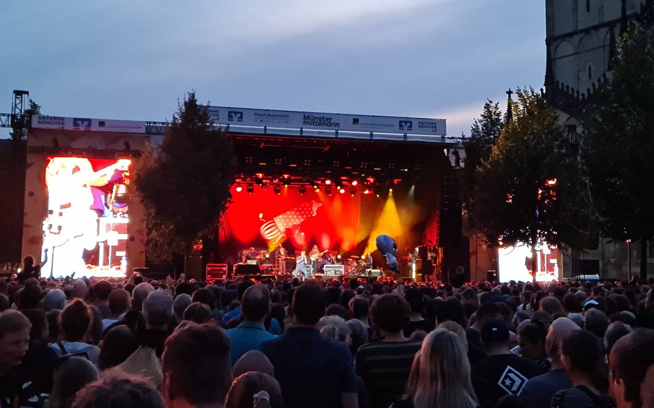 Eine Menge von Menschen steht mit dem Blick in Richtung einer Bühne. Die Bühne ist rot beleuchtet.