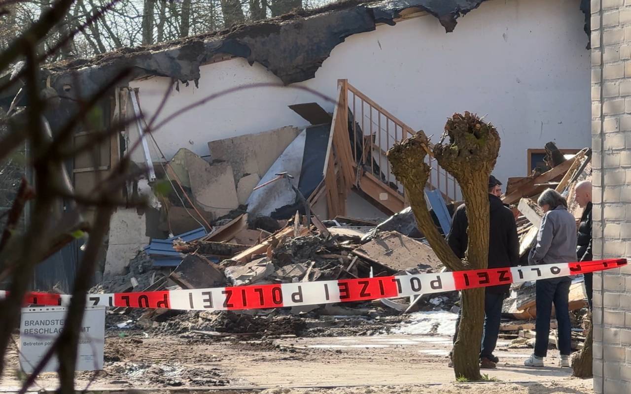 Hinter einem weiß-roten Flatterband sieht man Trümmer eines Gebäudes.
