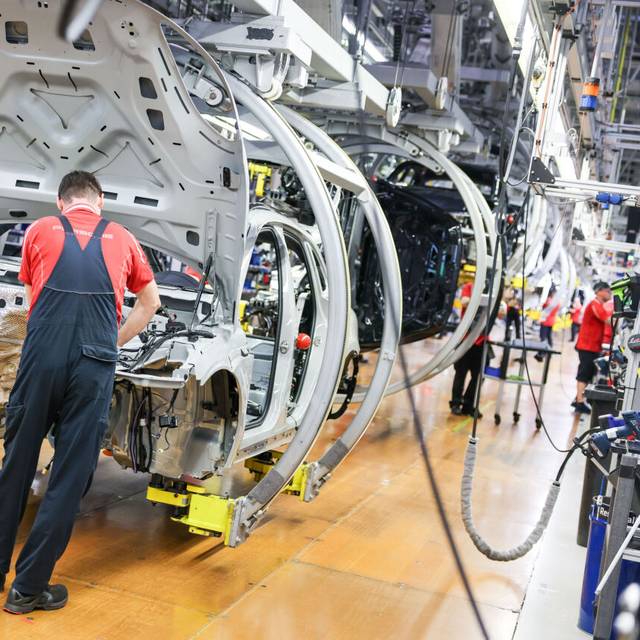 Ein Mitarbeiter montiert einen Porsche Macan in einem Werk.