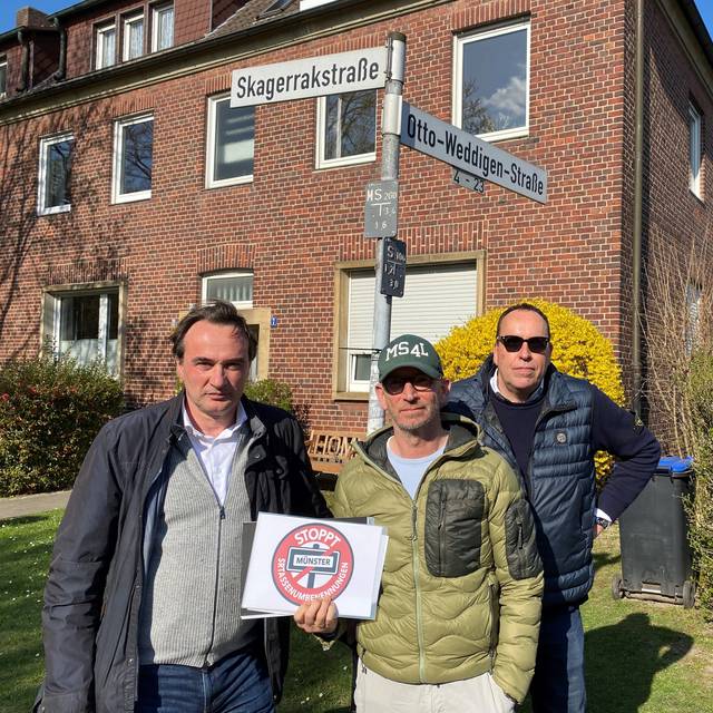 Drei Männer stehen an einer Straßenkreuzung.