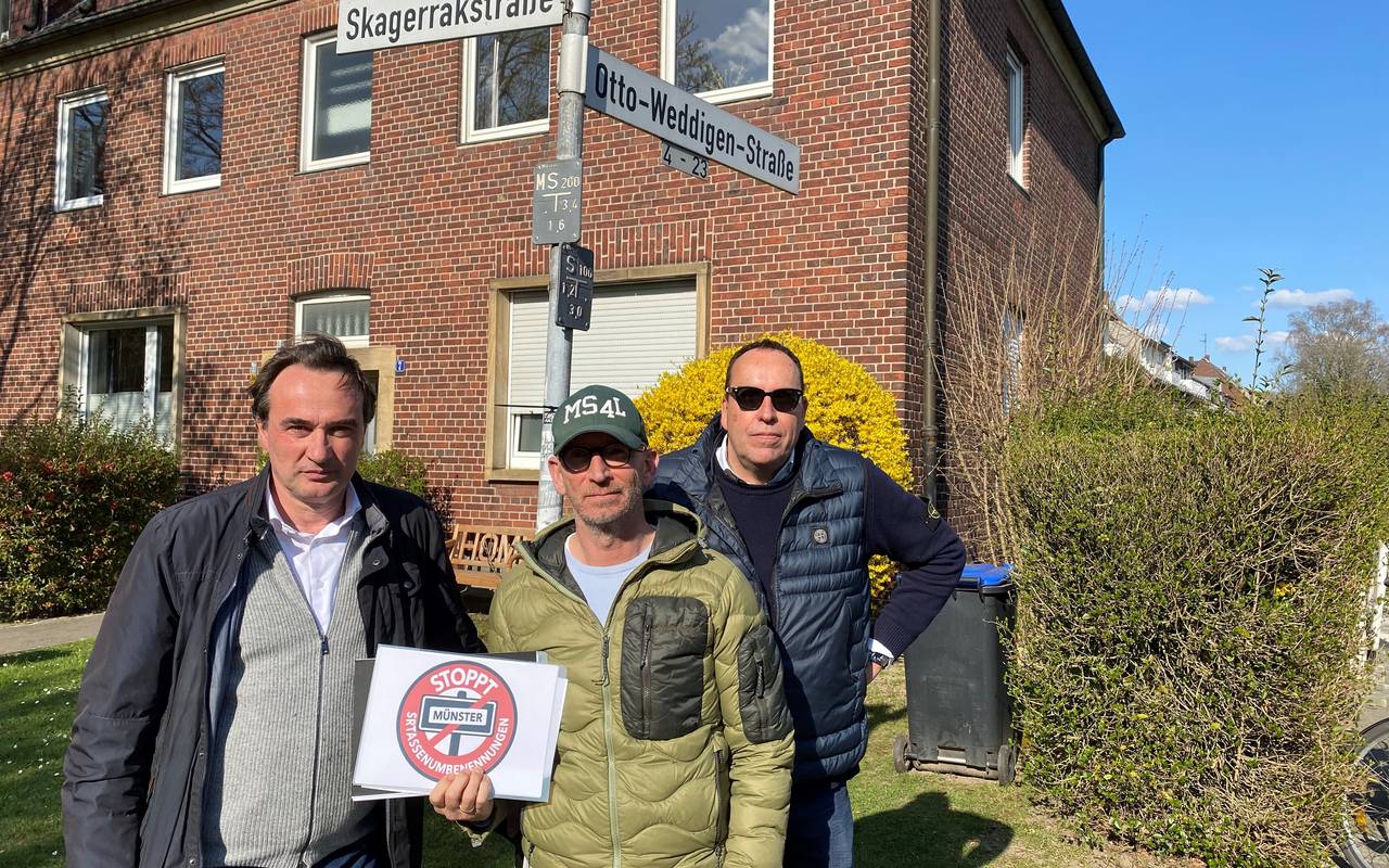 Drei Männer stehen an einer Straßenkreuzung.