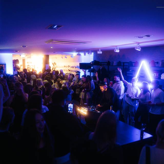 In einem kleinen Verkaufsraum feiern mehrere Menschen im dunklen Disco-Licht.