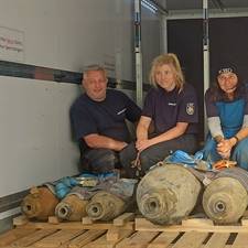 Fünf Menschen hocken auf einer Ladefläche und präsentieren die entschärften Blindgänger.