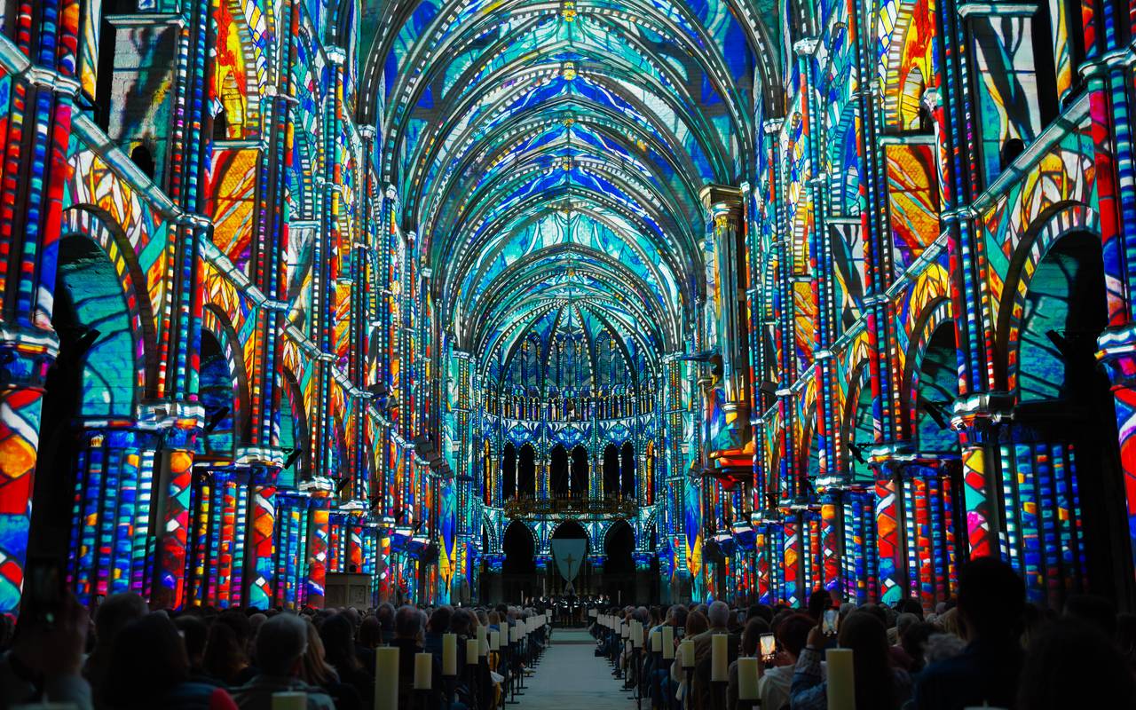 Eine dunkle Kirche ist mit farbigen Lichtern ausgeleuchtet.