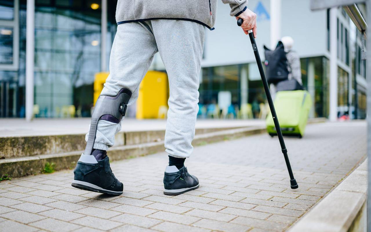 Ein Mann läuft mit einer Gehhilfe auf der Straße