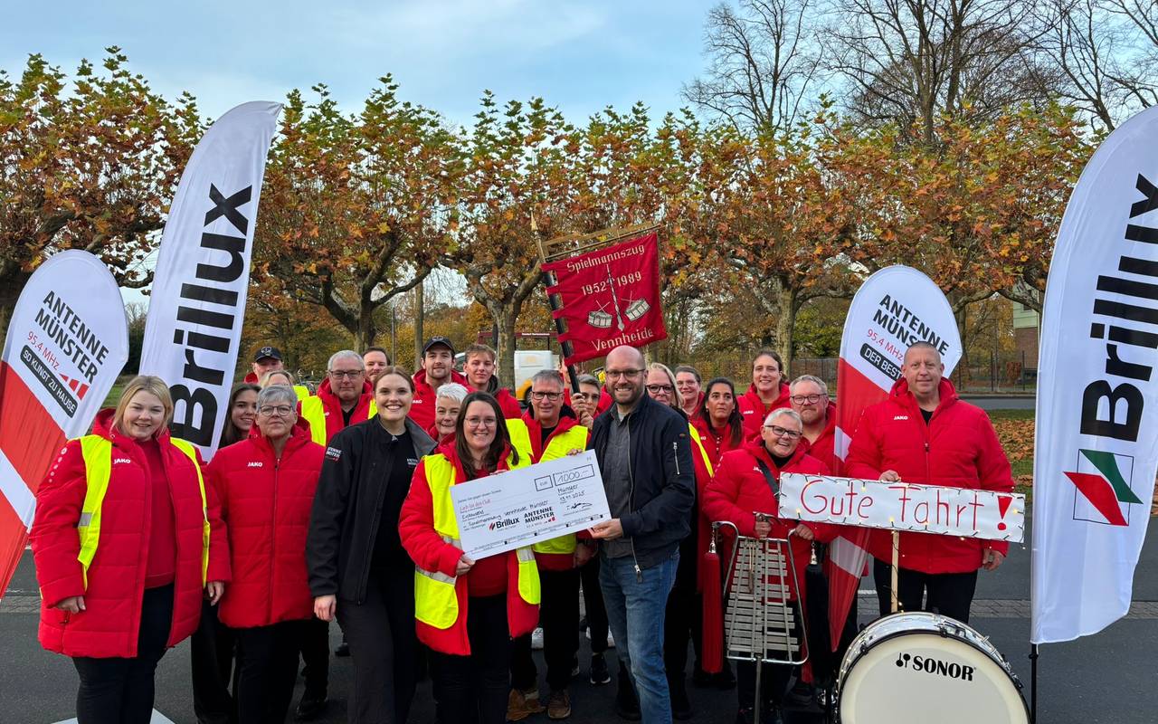 Malena Söhler aus der ANTENNE MÜNSTER-Morningshow "Zusammen wach" übergibt dem Spielmannszug Vennheide den Scheck über 1.000 Euro.