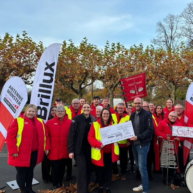 Malena Söhler aus der ANTENNE MÜNSTER-Morningshow "Zusammen wach" übergibt dem Spielmannszug Vennheide den Scheck über 1.000 Euro.