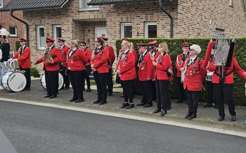 Ein Spielmannszug in rot-schwarzer Uniform auf einem Gehweg.