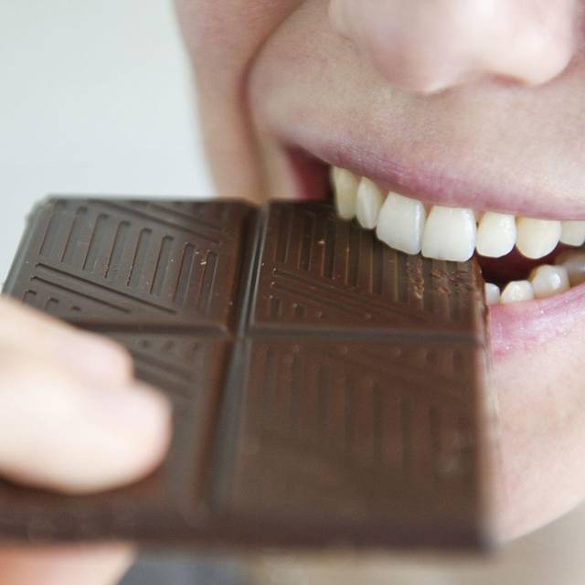 Frau beißt in ein Stück Schokolade