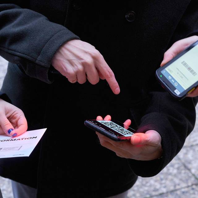 Ein Mann zeigt auf einen QR-Code den eine Frau Scannt