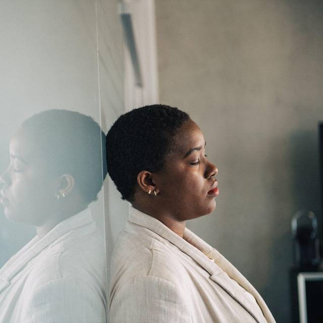 Eine junge Frau lehnt nachdenklich an einer Glaswand