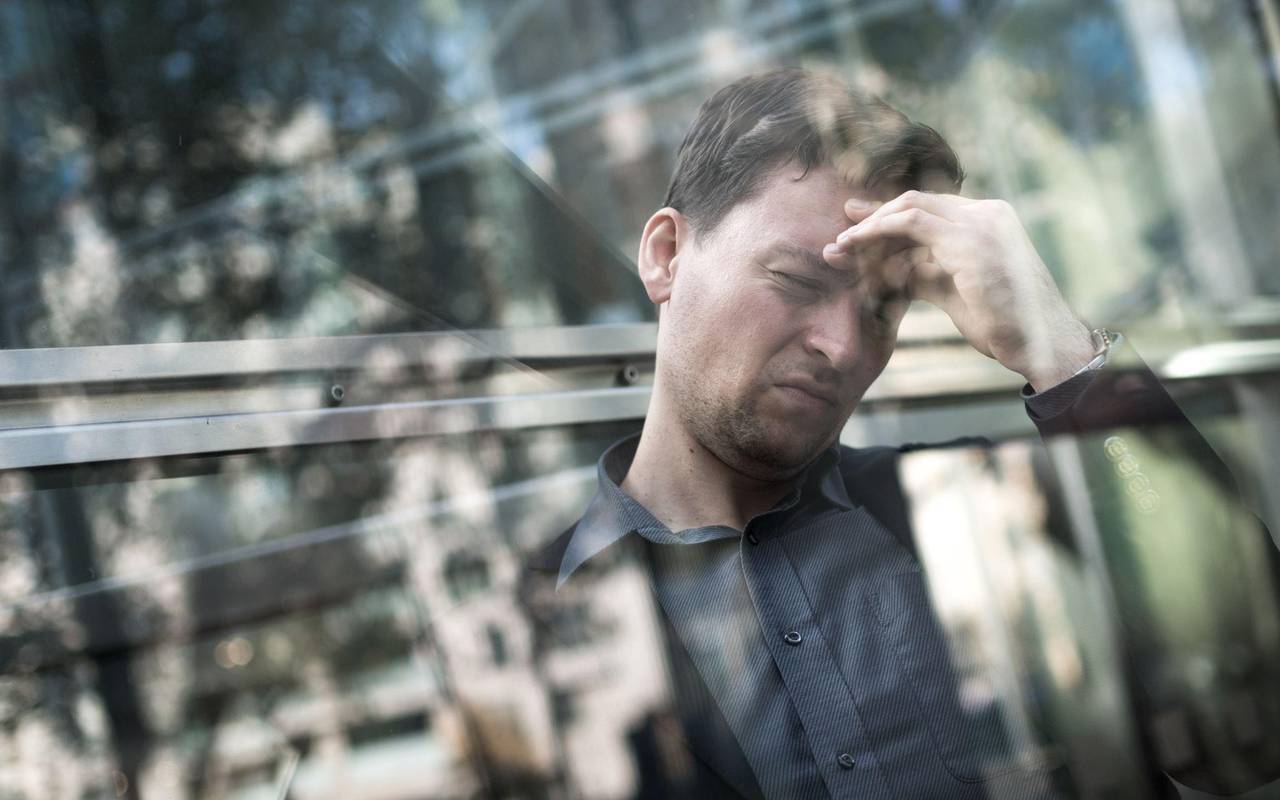 Mann hält sich mit der Hand seinen schmerzenden Kopf