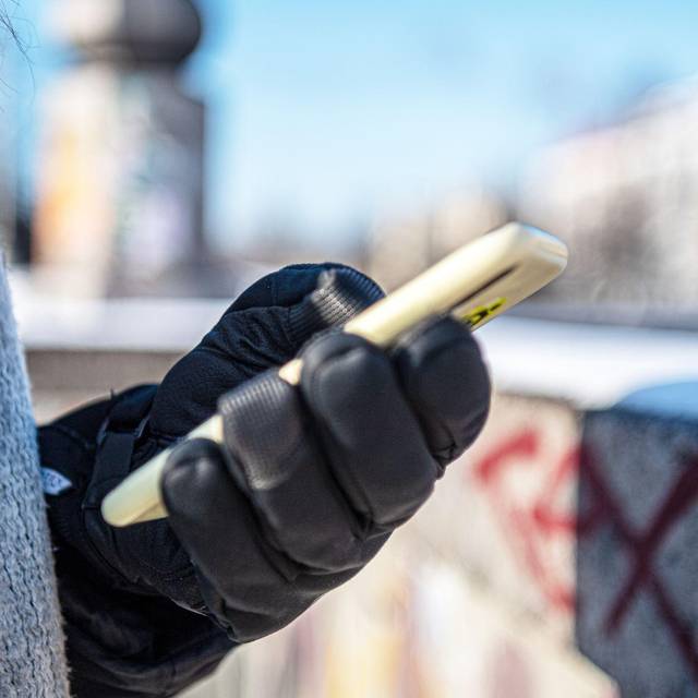 Eine warm angezogene Frau hält bei Kälte ein Handy
