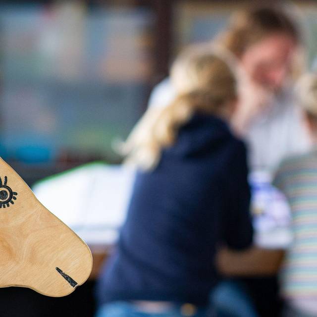 Ein Elternteil sitzt mit seinen Kindern an einem Tisch