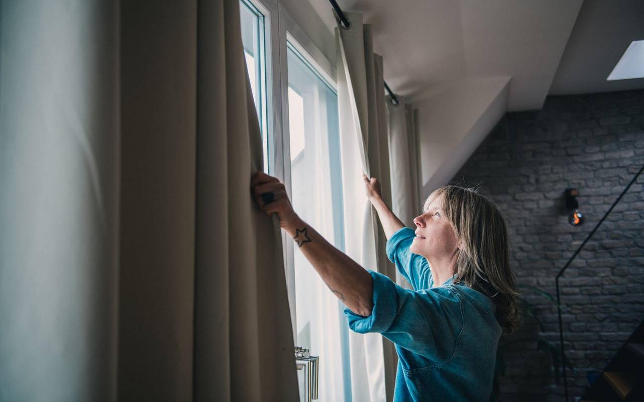 Eine Frau steht vor geöffneten Vorhängen