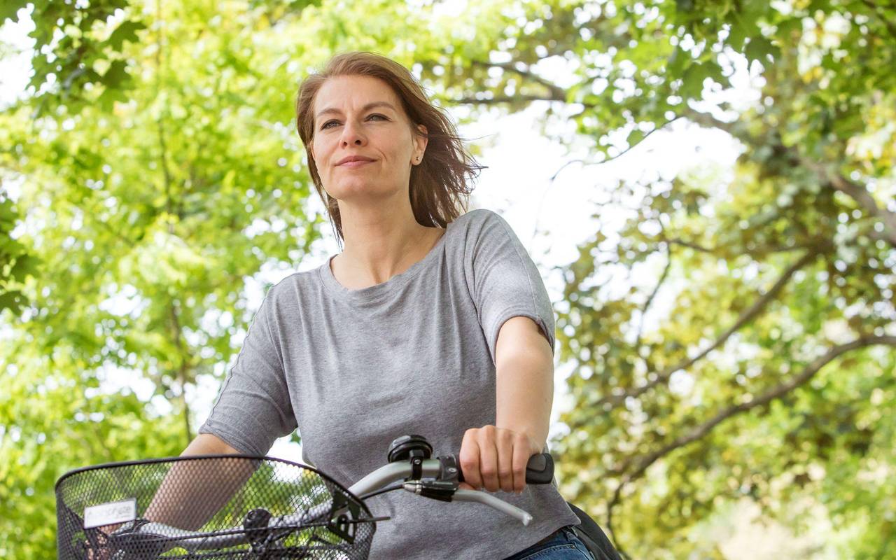 Frau fährt mit Fahrrad durch einen Park
