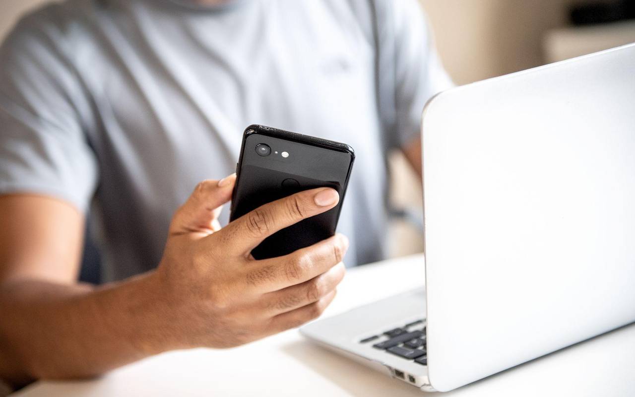 Mann mit Smartphone und Laptop