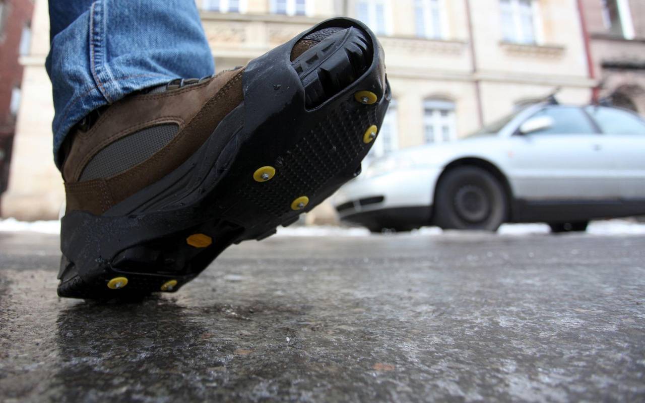 Ein Mann geht mit einer Spikes-Sohle über Eis