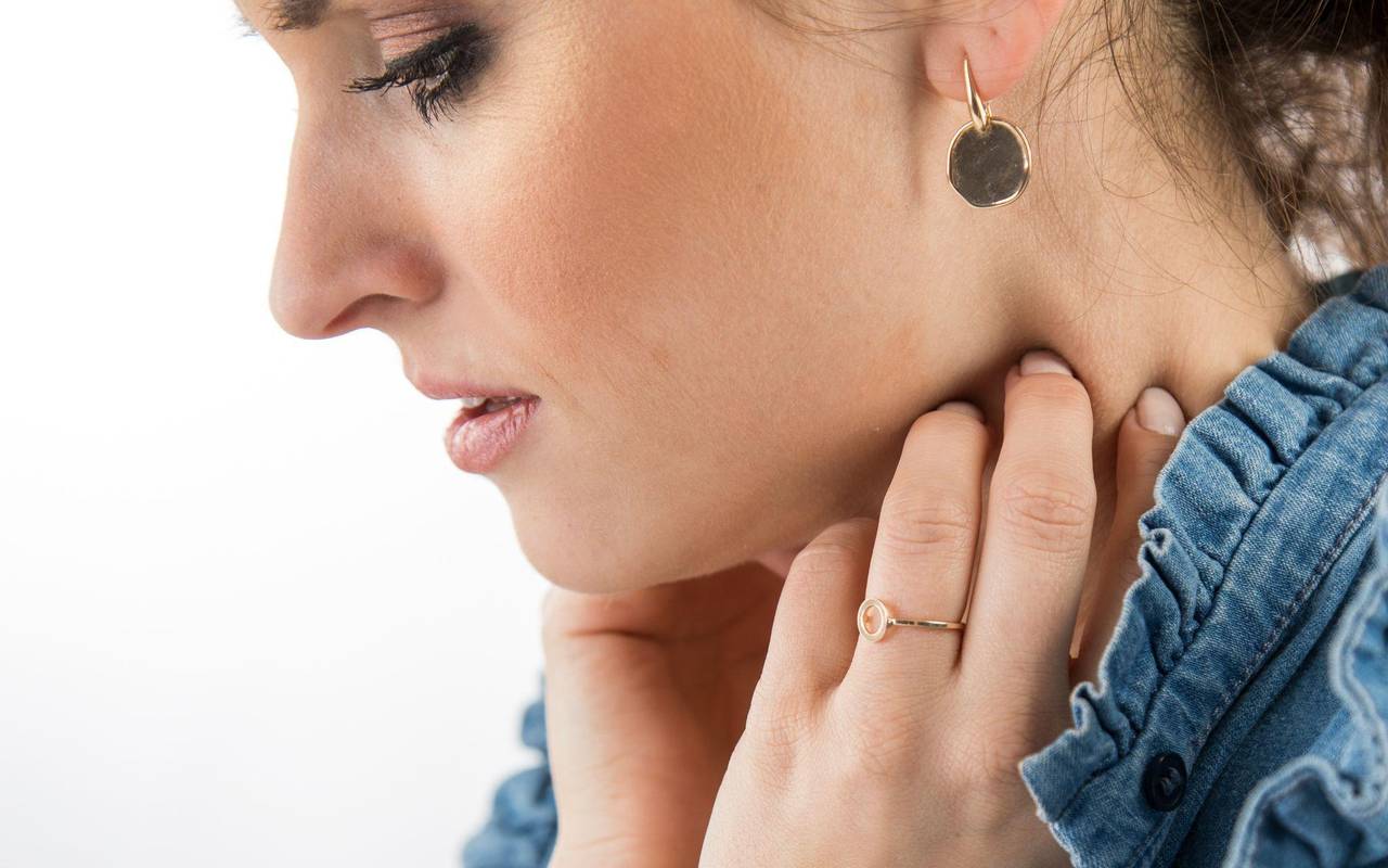 Frau fasst sich an den Hals