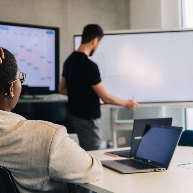 Eine Frau fasst sich an den Kopf in einem Meetingraum