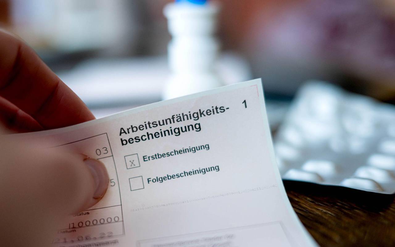 Eine Person hält eine Arbeitsunfähigkeitsbescheinigung