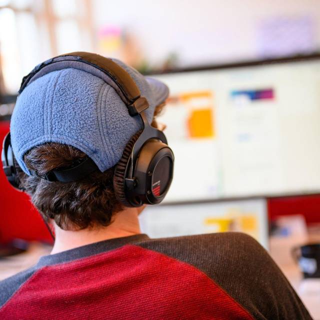 Ein Mitarbeiter mit Kopfhörern vor einem Computer-Bildschirm
