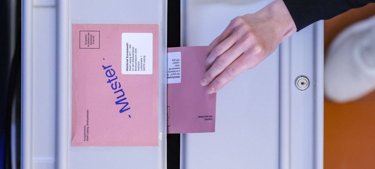 Eine Frau wirft den Umschlag mit dem Stimmzettel für die Europawahl in eine Wahlurne in der eröffneten Briefwahlstelle im Neuen Rathaus der Stadt Leipzig.