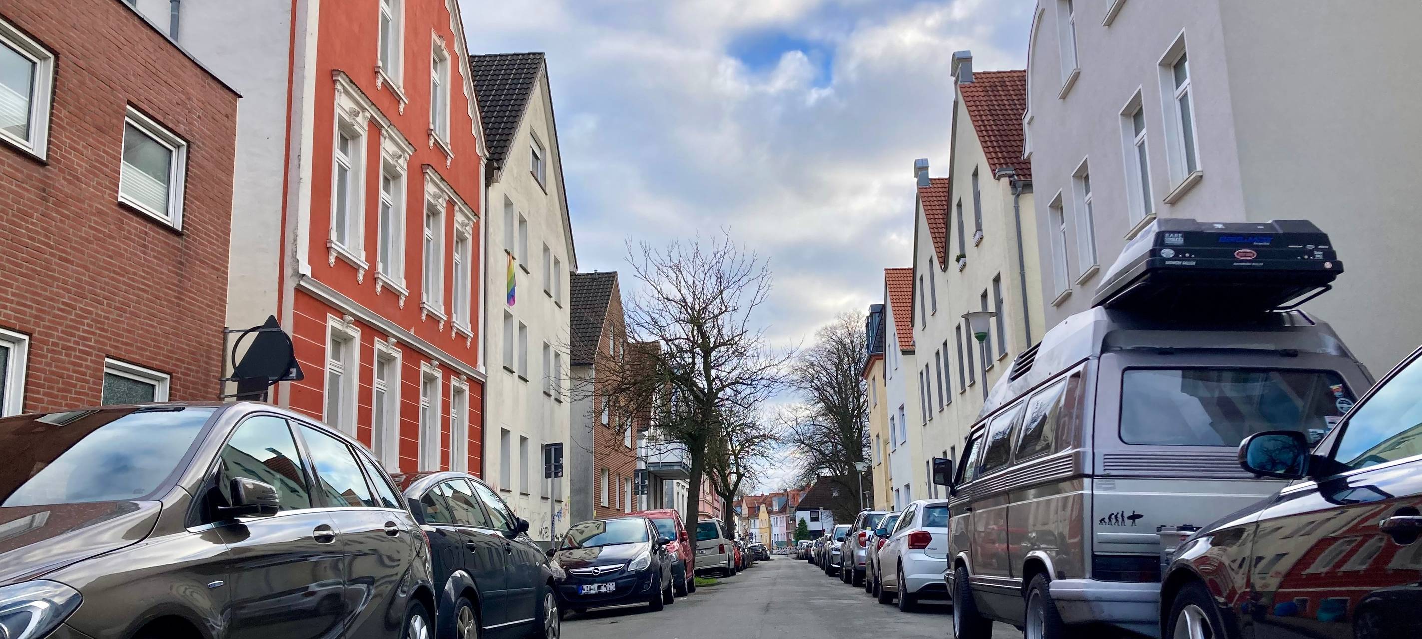 Parkende Autos auf beiden Seiten einer Straße.