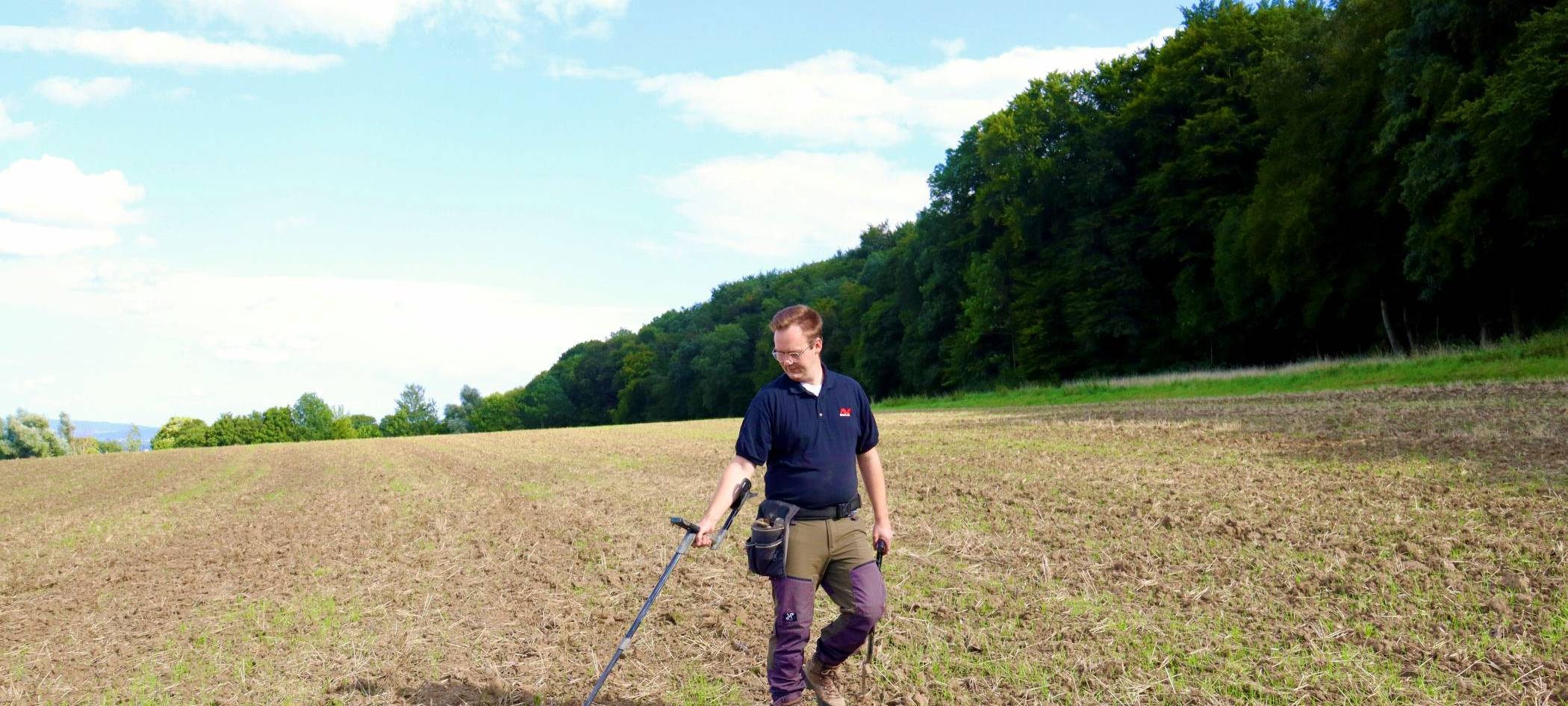 Ein Mann mit einem Metalldetektor auf einem Acker.