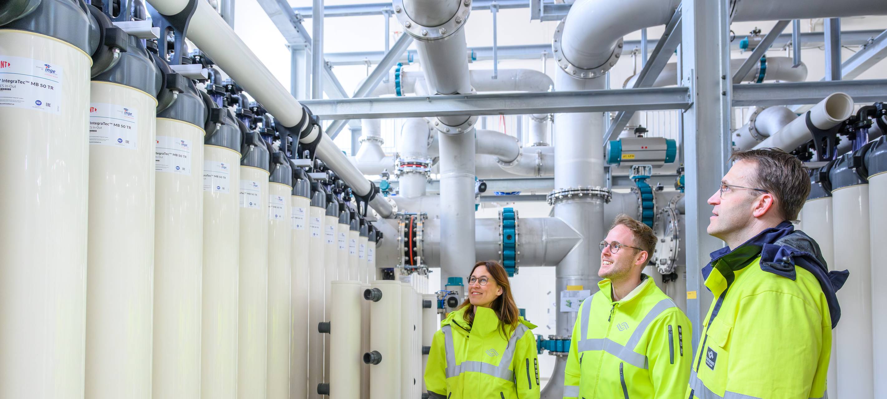 Eine Frau und zwei Männer in einem Wasserwerk.