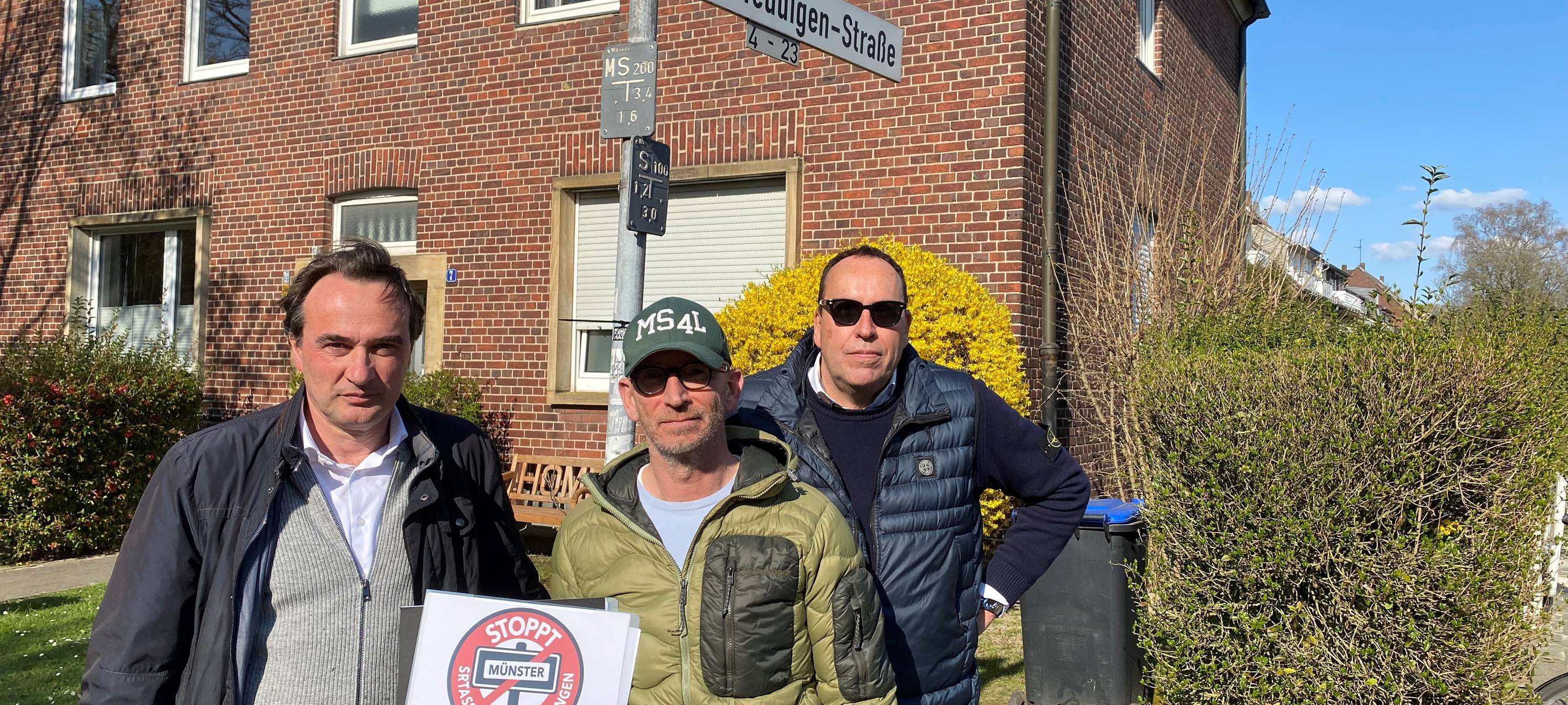 Drei Männer stehen an einer Straßenkreuzung.