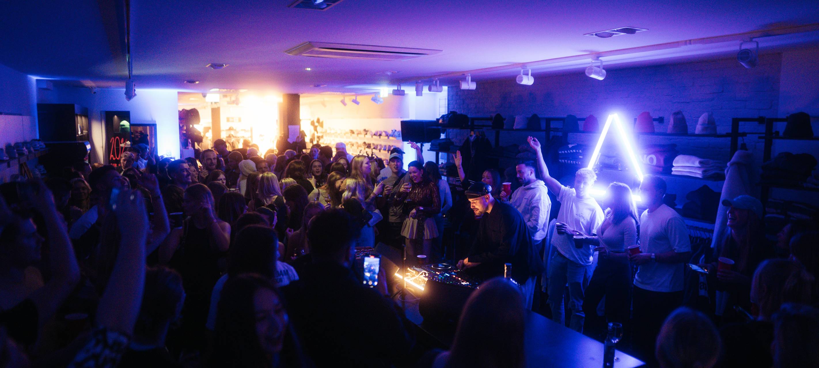In einem kleinen Verkaufsraum feiern mehrere Menschen im dunklen Disco-Licht.