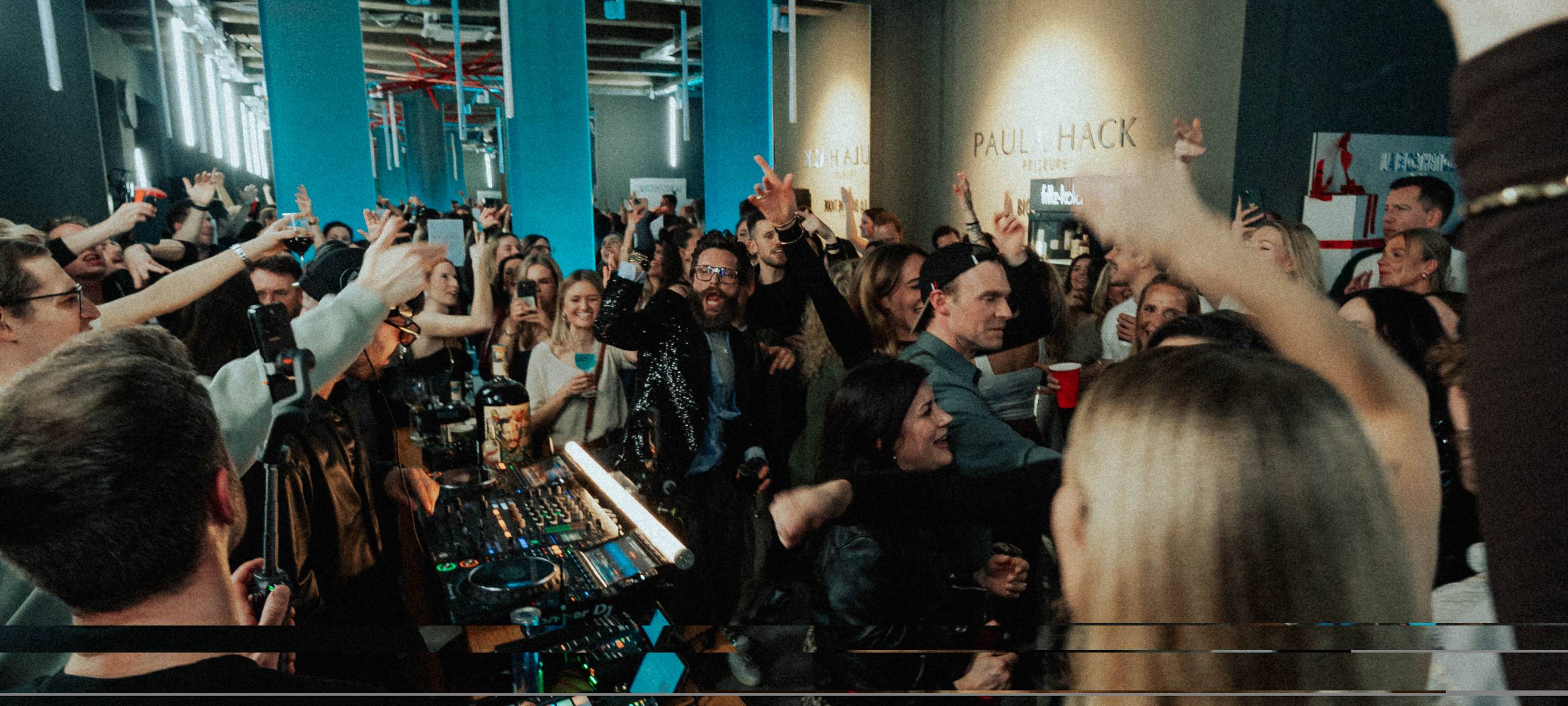 In einem kleinen Verkaufsraum feiern mehrere Menschen im dunklen Disco-Licht.