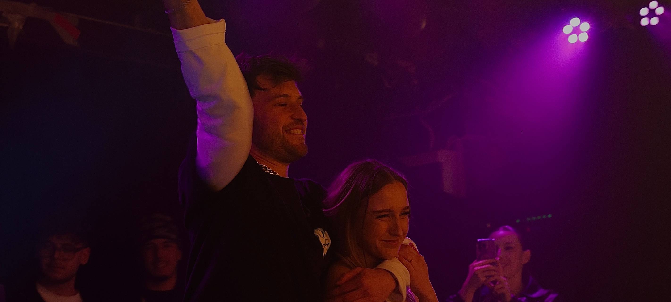 Der Sänger SLAY reckt seinen Arm in die Höhe. Im Anderen Arm hat er Soelna, die ein Mikrofon in der Hand hält.