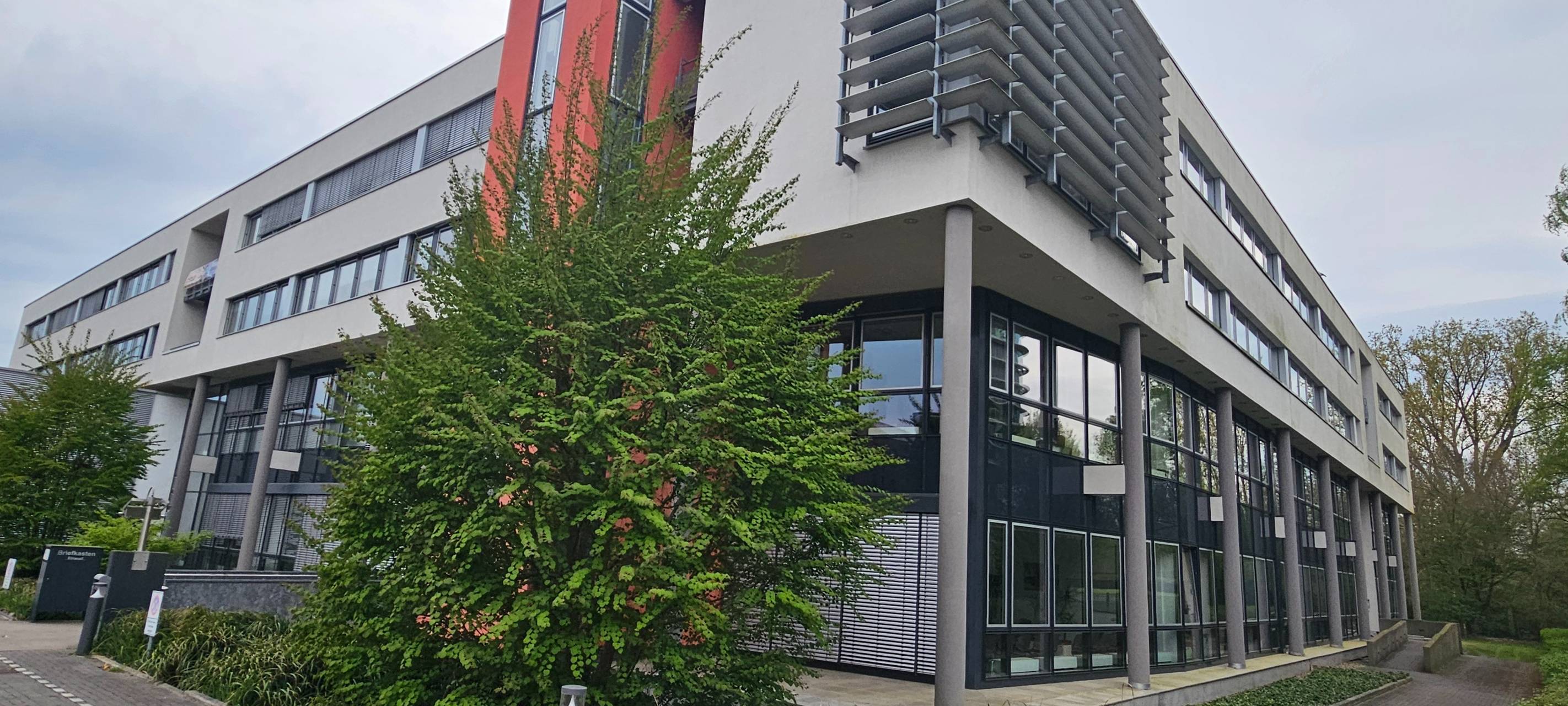 Das Gebäude des Finanzamt Münster-Innenstadt von außen. Ein modernes Gebäude mit weißer Fassade und roten Akzenten.