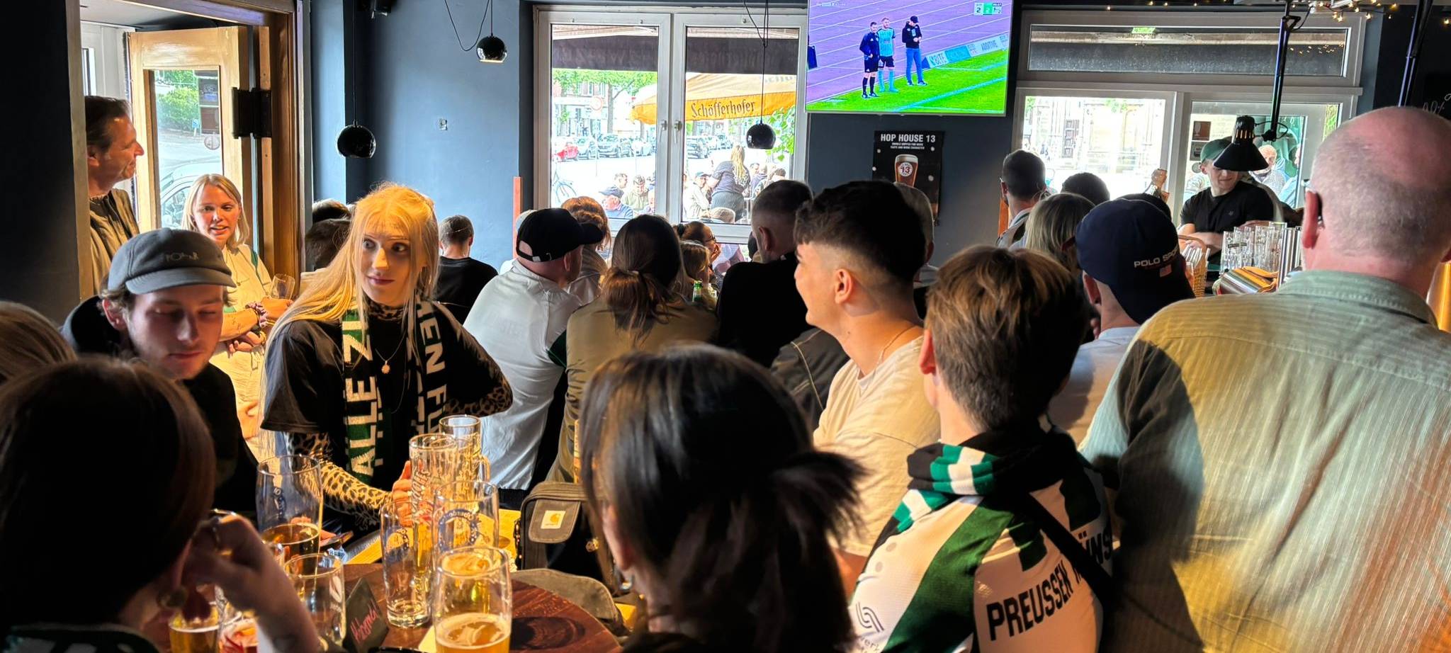 Fußballfans schauen gemeinsam ein Spiel in einer Kneipe.