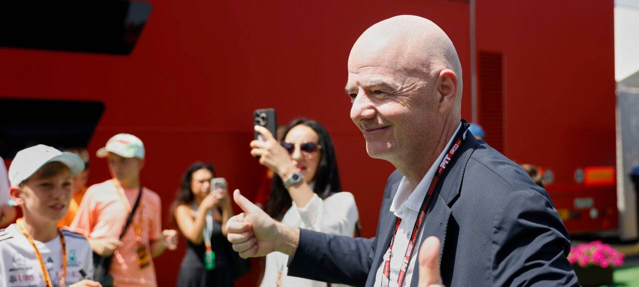 Gianni Infantino, Präsident der FIFA, schaut lächelnd und mit gestrecktem Daumen in Kameras.