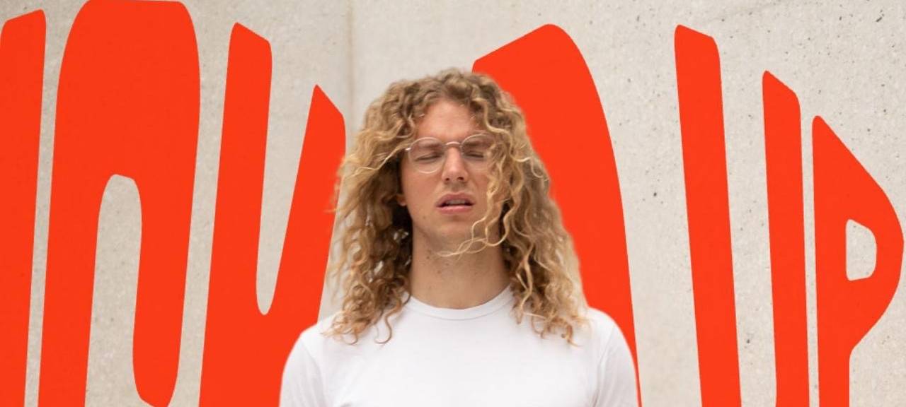 Das Cover der neuen Single von Equa Tu. Darauf sieht man Equa Tu, ein Mann mit langen, blonden Locken und einer Brille.