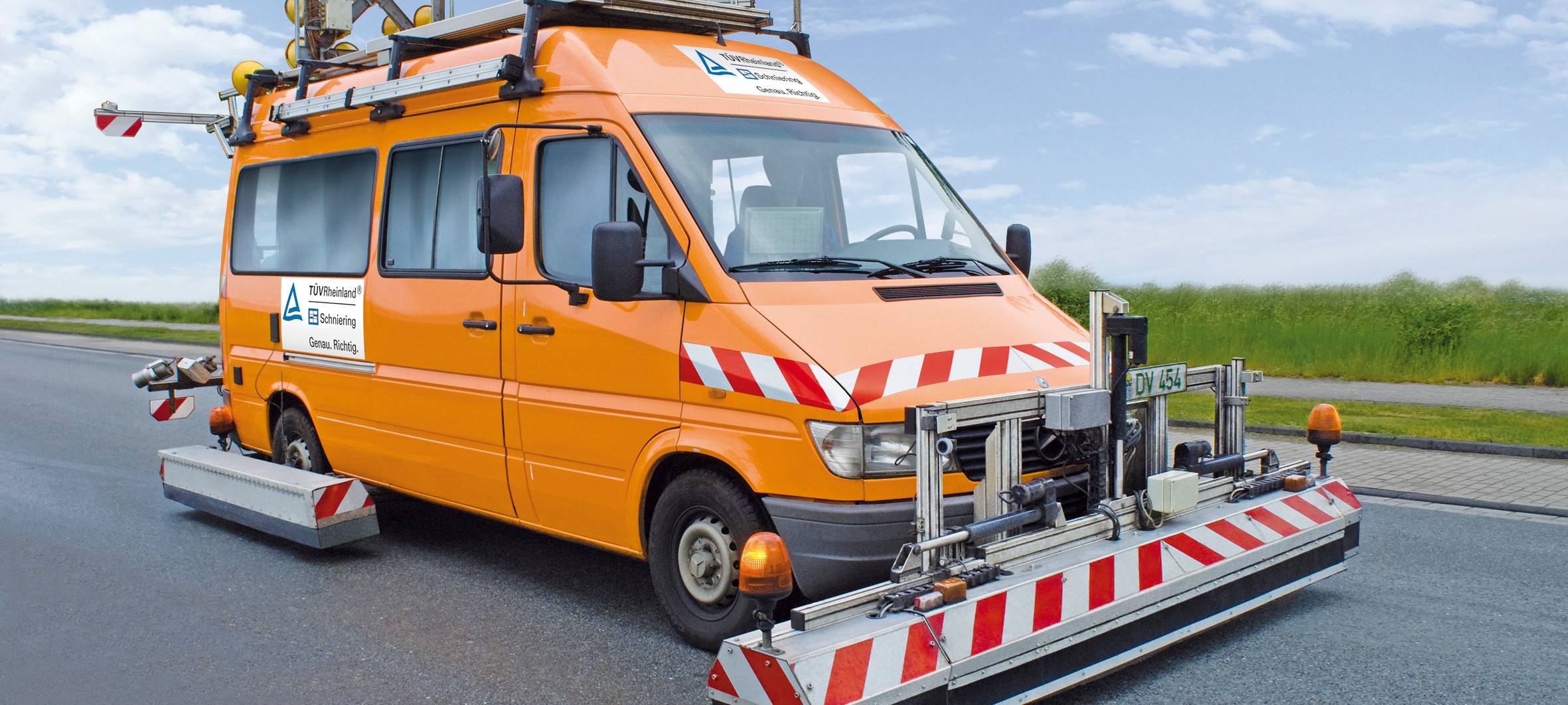 Ein großes orangenes Fahrzeug mit mehrere Gestellen am unteren Rand, die knapp über dem Boden enden.