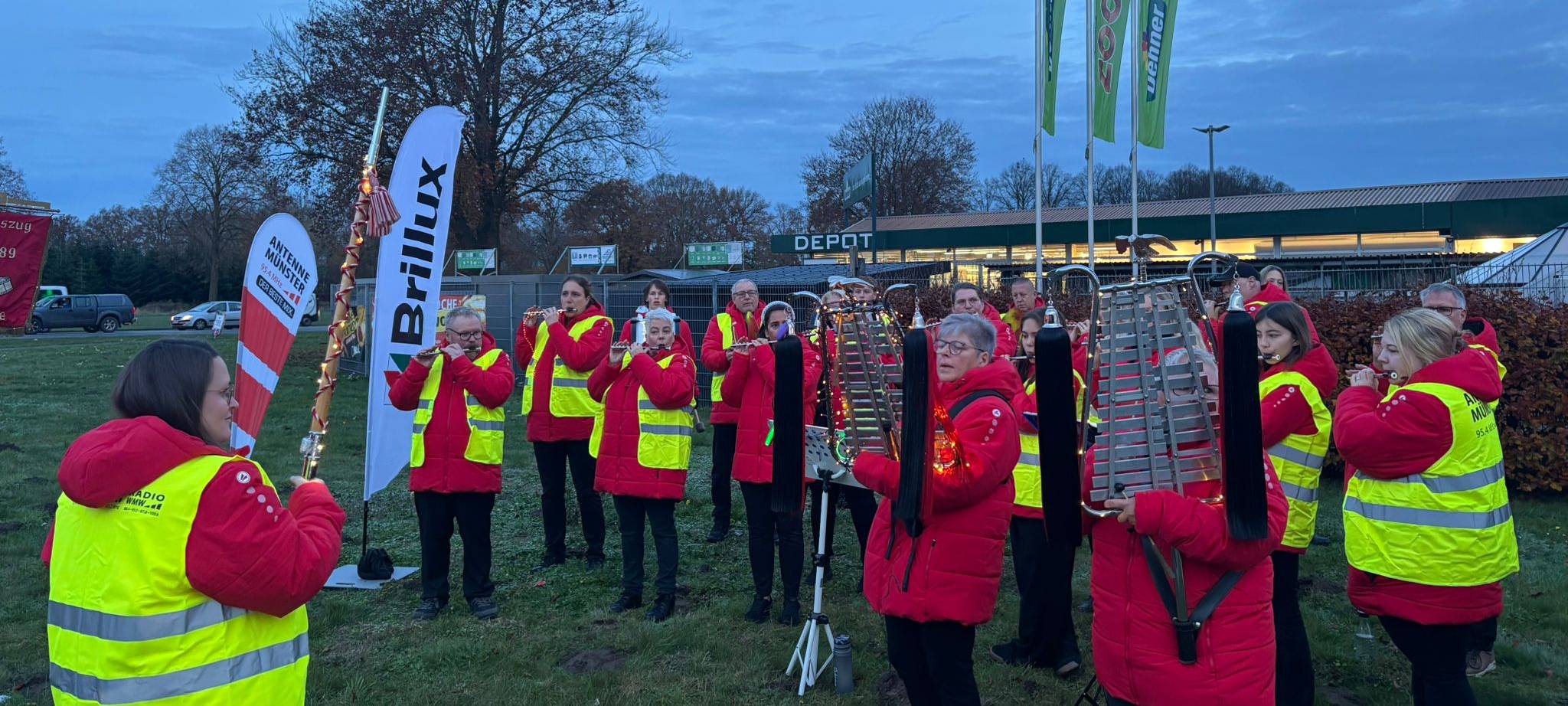 In der morgendlichen Dämmerung steht der Spielmannszug Vennheide auf einer Wiese neben der Warendorfer Straße und spielt.