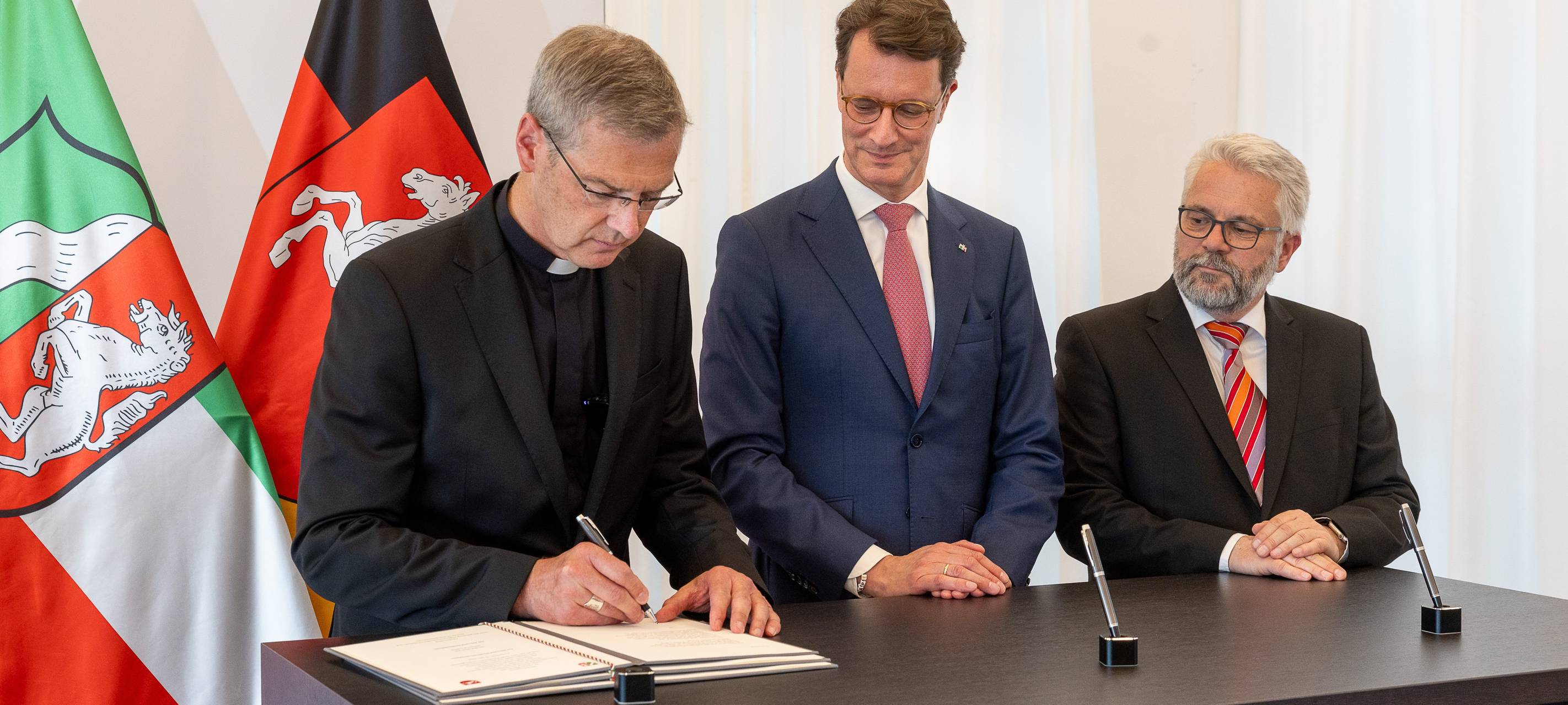 Bischof Dr. Heiner Wilmer SCJ legt den Treueeid ab. Das Bild zeigt von links Bischof Dr. Heiner Wilmer SCJ, NRW-Ministerpräsident Hendrik Wüst (CDU), Carsten Milde als Vertreter der niedersächsischen Landesregierung.