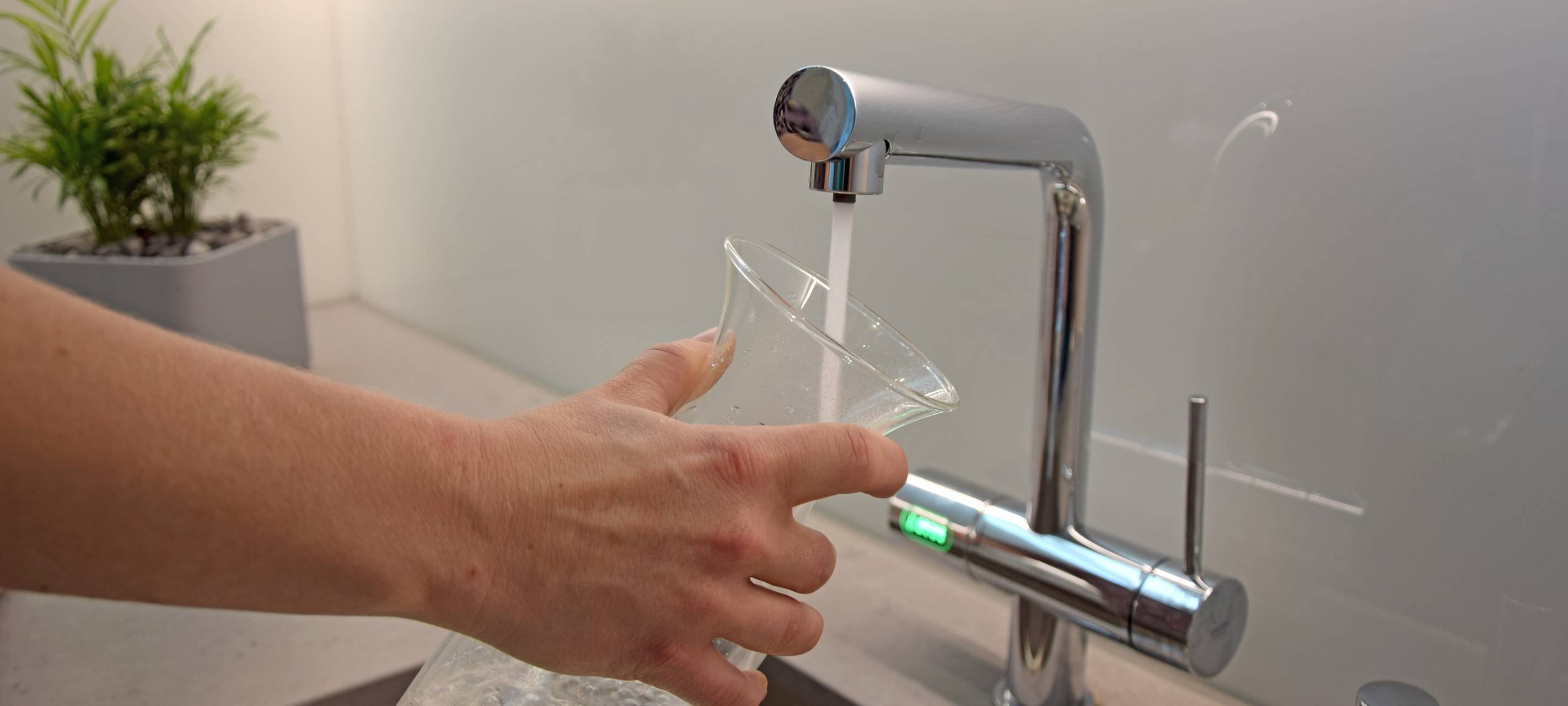 An einem Wasserhahn wird ein Glas gefüllt.