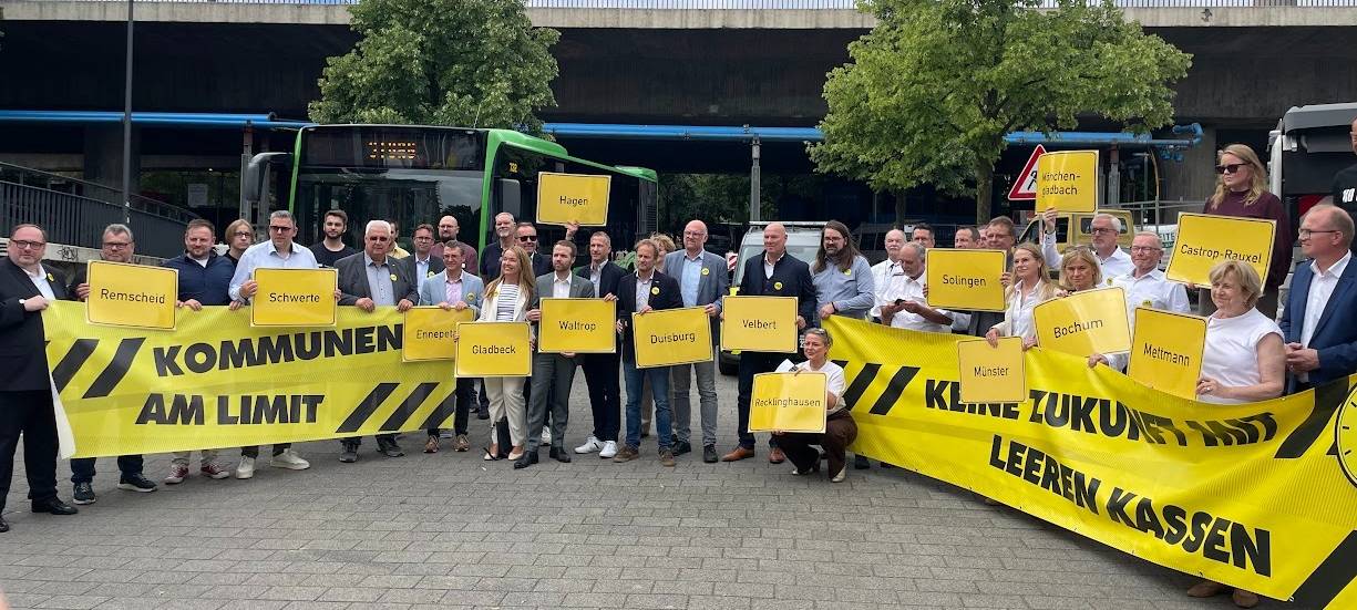 Bürgermeister und Kämmerer NRWs halten Plakate hoch