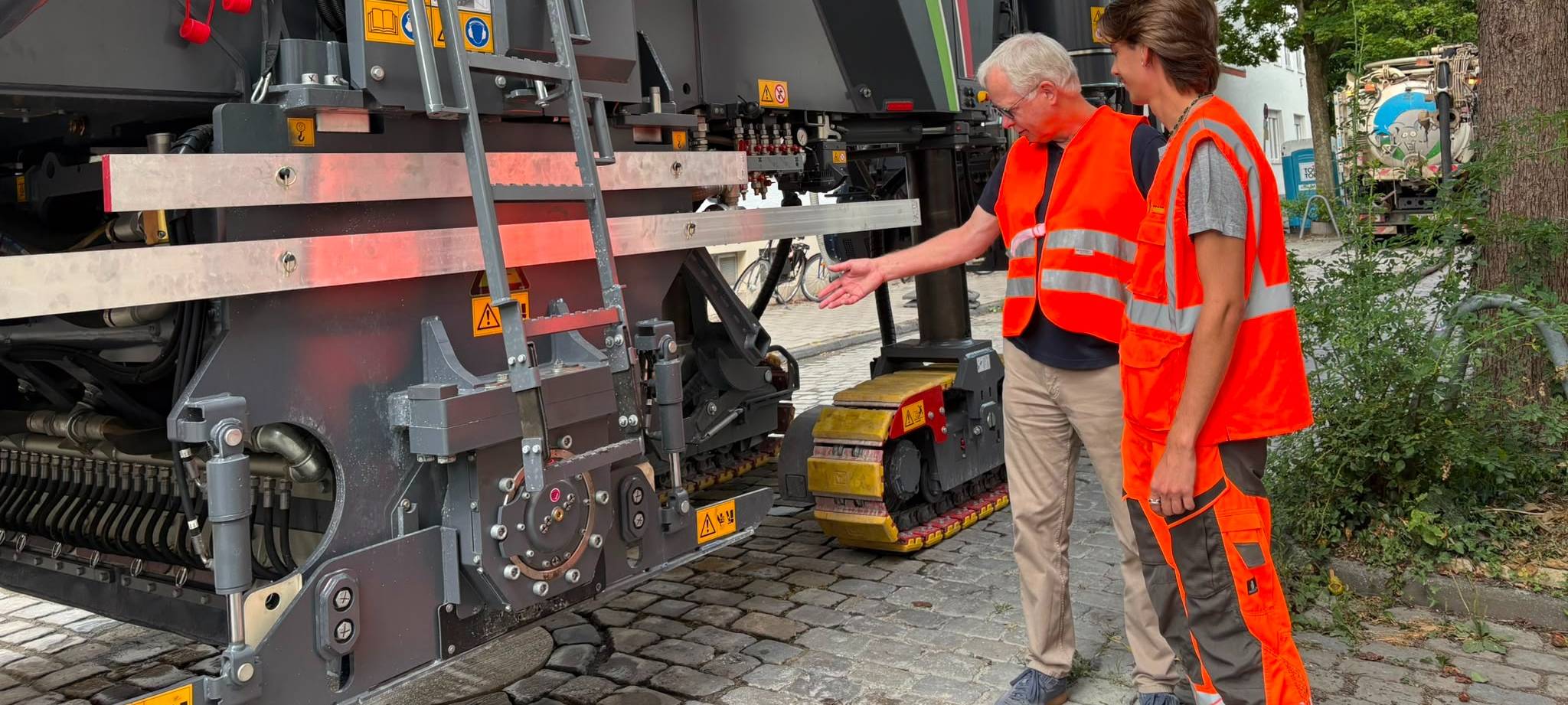 Leitung des Amtes für Mobilität und Tiefbau Gerhard Rüller (links) und der Geschäftsführer Fräsdienst-Service E. Feind GmbH Eric Feind (rechts) stehen vor der Fräsmaschine.