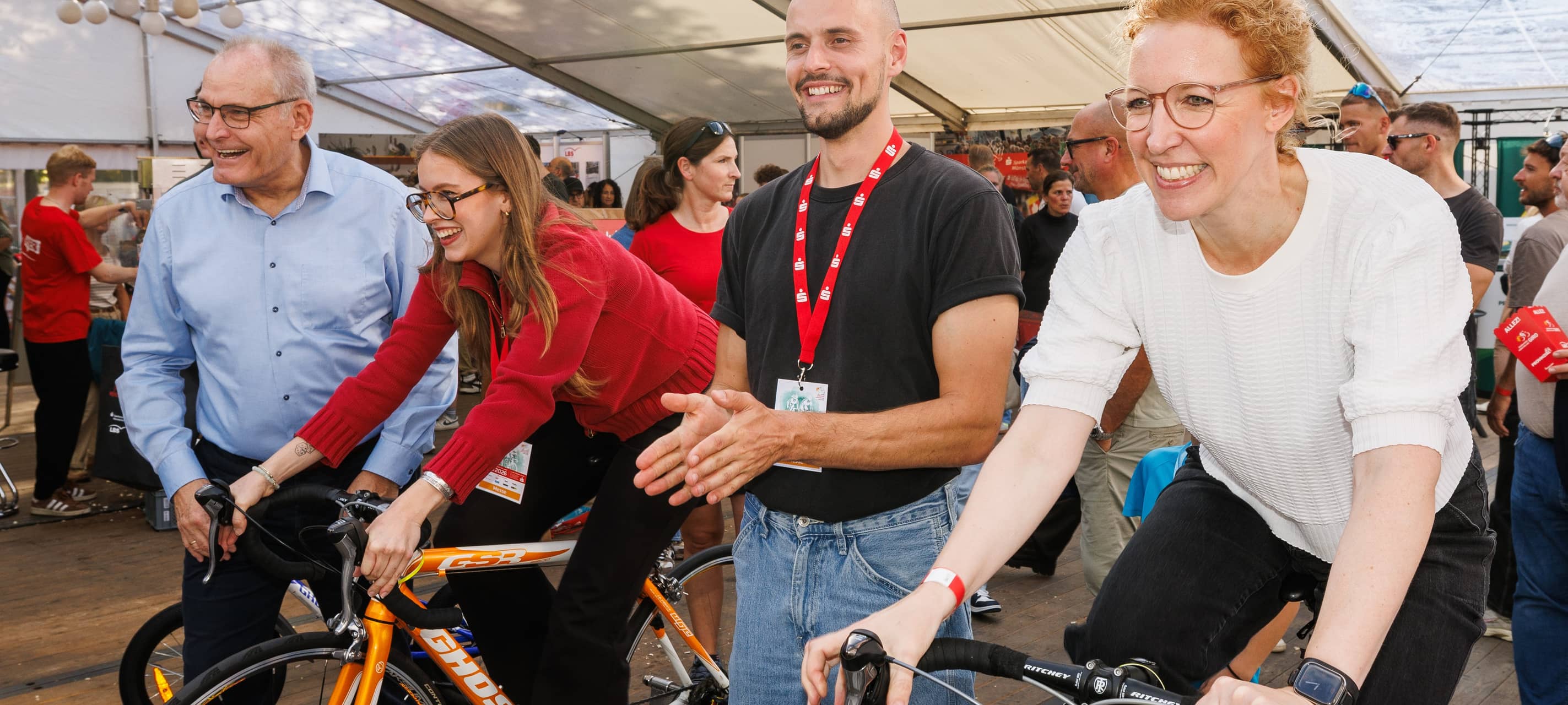 Peter Scholz, stellvertretender Vorstandsvorsitzender der Sparkasse Münsterland Ost (auf dem Foto links) und Vorständin Dr. Annegret Saxe (r.) setzten sich im Messezelt gleich selbst auf den Rennradsimulator und strampelten gemeinsam mit dem Vorstandsteam vom Ehrenort (Frieda Kremp, 2.v.l., und Jakob Schoen, 2.v.r.) weitere wertvolle Meter zusammen.