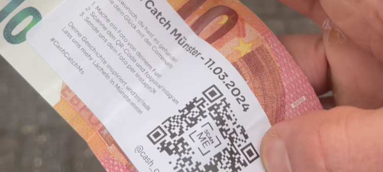 Ein 10 Euro-Schein, auf dem ein Sticker klebt. Der Sticker weist auf den instagram-Kanal @cash_catch_ms hin.